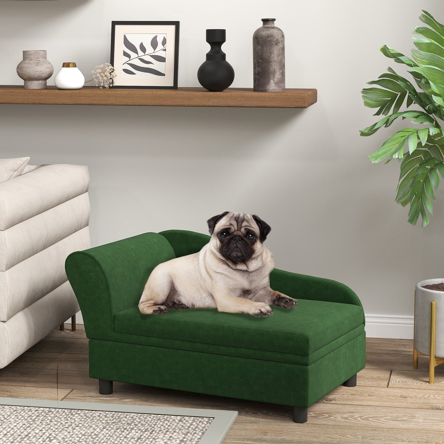 Pug lying on a green pet bed in a living room setting with a shelf and plant in the background.